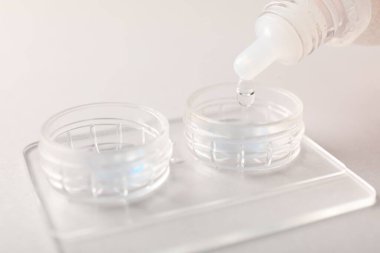 Işık arkaplanındaki kontakt lenslerle birlikte çözelti dosyaya damlıyor, yakın plan