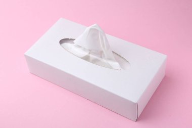 Pembe arka planda kağıt mendilli bir kutu.