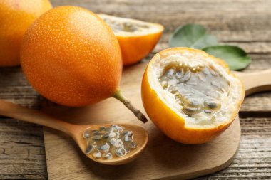 Olgun tutku meyveleri, tohumlar ve yeşil yapraklar ahşap masada, yakın plan.