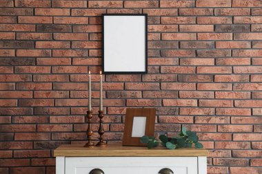 Mum ve tuğla duvarın yanındaki masada yanan mumlar.