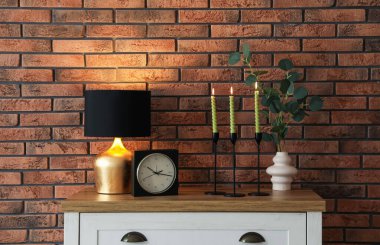 Mum ve tuğla duvarın yanındaki masada yanan mumlar.