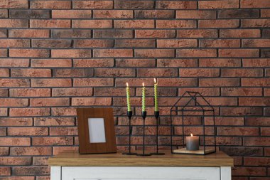 Mum ve tuğla duvarın yanındaki masada yanan mumlar.