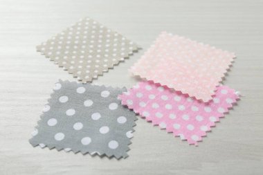 Beyaz ahşap masadaki farklı kumaşlardan örnekler, yakın plan.