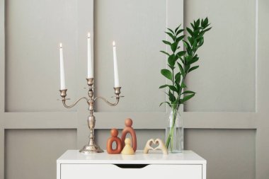 Işık duvarının yanındaki çekmecelerde yanan mumlar ve dekorlarla süslü zarif bir şamdan.
