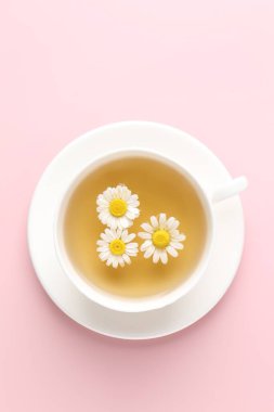 Fincanda nefis papatya çayı ve pembe arka planda taze çiçekler.