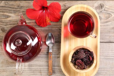 Cam fincanda leziz amber çayı, çaydanlık, kuru gül sepals ve tahta masada çiçek, düz uzanmış