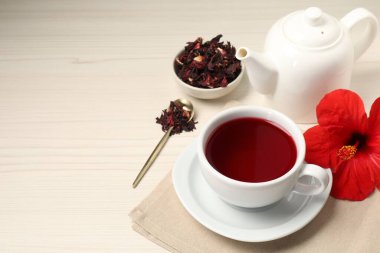 Lezzetli bardakta amber çayı, çaydanlık, kuru roselle sepals ve açık ahşap masada çiçek, metin için yer