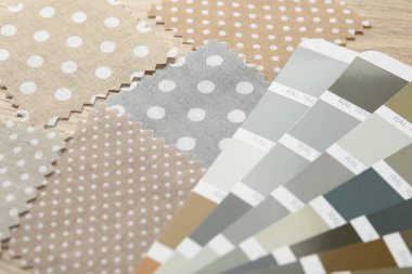 Ahşap masada renkli kumaş örnekleri ve renk paletleri, yakın plan.