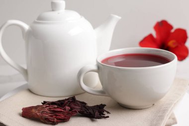 Fincanda leziz amber çayı, çaydanlık ve kuru roselle sepals beyaz masada, yakın plan.