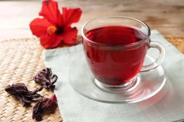 Cam bardakta leziz amber çayı ve ahşap masada kuru roselle sepals, yakın plan.