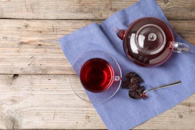 Cam fincanda leziz amber çayı, çaydanlık, kuru roselle sepals ve tahta masada kaşık, düz yatak. Metin için boşluk