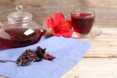 Cam fincanda leziz amber çayı, çaydanlık, kuru roselle sepals ve ahşap masada kaşık, yakın plan. Metin için boşluk