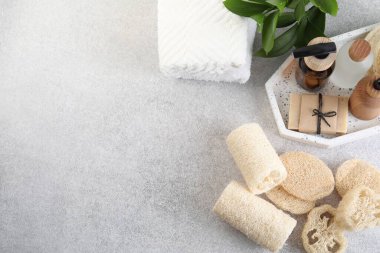 Değişik lif süngerleri, havlular ve kozmetik ürünler açık gri masada, düz yerde. Metin için boşluk