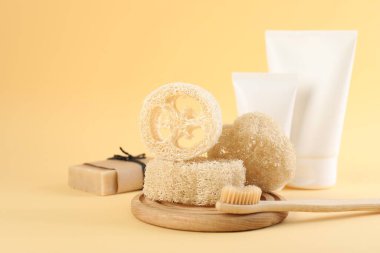 Lif süngeri, diş fırçası, bej arka planda kozmetik ürünler ve sabun tüpleri, yakın plan. Metin için boşluk