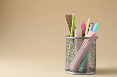 Bej arka planda kalem tutacağında farklı bir kırtasiye malzemesi. Metin için boşluk