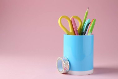 Pembe arka planda kalem tutacağında farklı bir kırtasiye malzemesi. Metin için boşluk