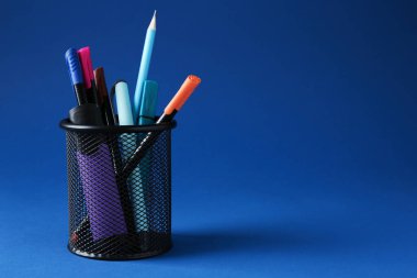 Koyu mavi arka planda kalem tutacağında farklı bir kırtasiye malzemesi. Metin için boşluk