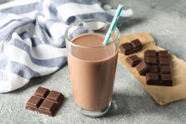 Lezzetli çikolatalı süt cam ve parçalar gri masada, yakın plan.