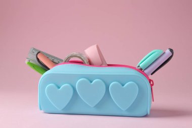 Pembe arka planda kalem kutusunda farklı kırtasiye malzemesi