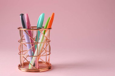 Pembe arka planda kalem tutacağında farklı bir kırtasiye malzemesi. Metin için boşluk