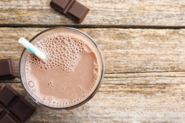Bardakta çikolatalı süt ve ahşap masada parçalar, düz bir şekilde. Metin için boşluk