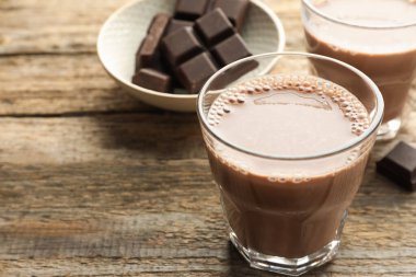 Bardakta çikolatalı süt ve ahşap masada parçalar, yakın plan. Metin için boşluk