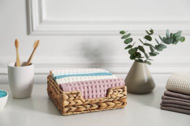 Temiz waffle havluları ve diğer banyo ürünleri banyodaki beyaz şifoniyerde.