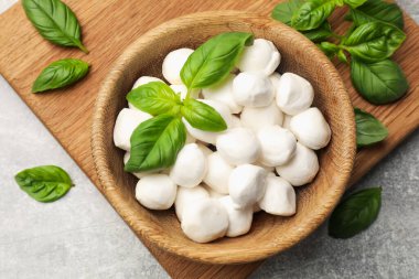 Mozzarella peynir topları ve fesleğen açık gri masada, düz yatıyordu.