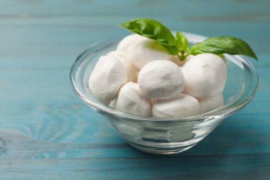 Mozzarella peynir topları ve fesleğen mavi ahşap masada, yakın plan.