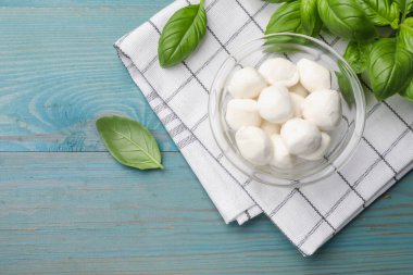 Mozzarella peyniri topları ve fesleğen mavi ahşap masada, düz yatıyordu.