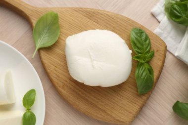 Ahşap masada mozzarella peyniri ve fesleğen var.