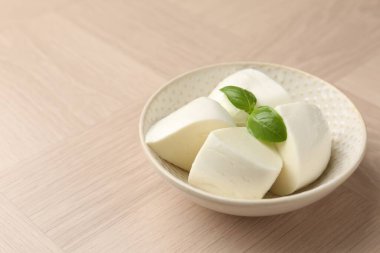 Ahşap masadaki fesleğen ve mozzarella peyniri parçaları, yakın plan. Metin için boşluk