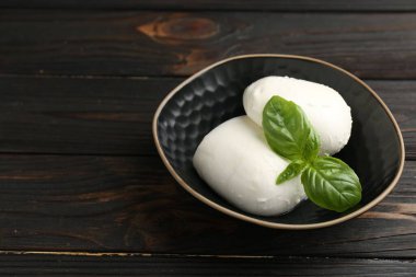 Ahşap masadaki fesleğen ve mozzarella peyniri parçaları, yakın plan. Metin için boşluk