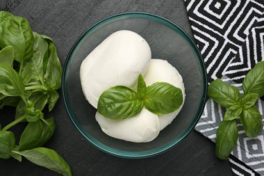 Lezzetli mozzarella peyniri ve fesleğen parçaları koyu dokulu masada, düz yerde.