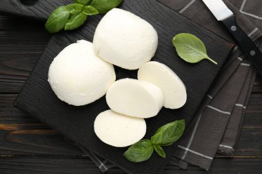 Lezzetli mozzarella peyniri ve fesleğen parçaları ahşap masada, düz yatıyordu.