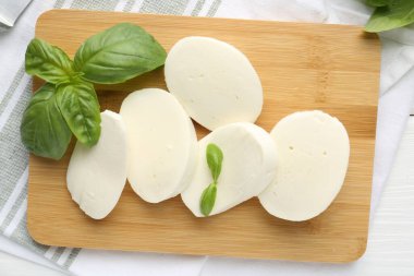 Lezzetli mozzarella peyniri ve fesleğen parçaları beyaz ahşap masa, düz yatıyordu.