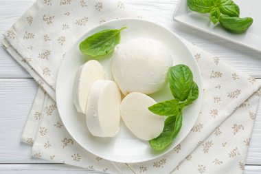 Lezzetli mozzarella peyniri ve fesleğen parçaları beyaz ahşap masa, düz yatıyordu.