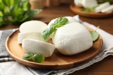 Nefis mozzarella peyniri parçaları ve fesleğen yaprakları ahşap masada, yakın plan.