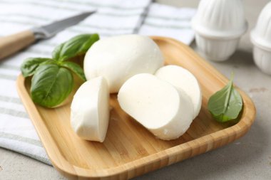 Lezzetli mozzarella peyniri ve fesleğen yaprakları. Gri desenli masa, yakın plan.