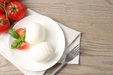 Lezzetli mozzarella peyniri topları, domates ve fesleğen, ahşap masa, düz yatak. Metin için boşluk