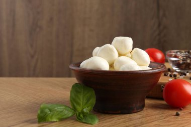 Lezzetli mozarella topları, domatesler, biberler ve fesleğenler ahşap masada, yakın plan. Metin için boşluk