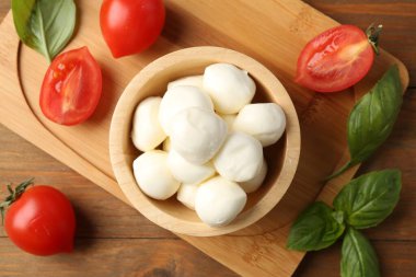 Lezzetli mozarella topları, domatesler ve fesleğenler ahşap masada, düz yatıyordu.