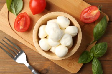 Lezzetli mozarella topları, domatesler ve fesleğenler ahşap masada, düz yatıyordu.