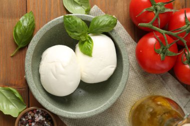 Lezzetli mozzarella topları, domatesler, ahşap masada yağ ve fesleğen.