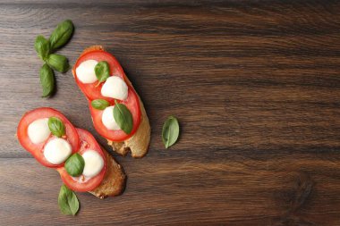 Peynirli, domatesli, ahşap masadaki fesleğenli lezzetli sandviçler. Metin için boşluk