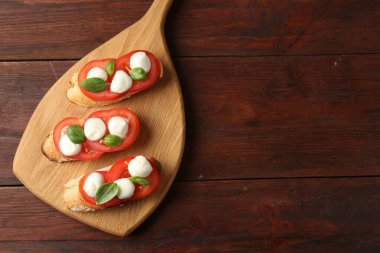 Mozarella peynirli, domatesli ve ahşap masadaki fesleğenli lezzetli sandviçler. Metin için boşluk