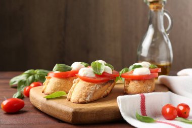 Mozarella peynirli, domatesli ve ahşap masadaki fesleğenli lezzetli sandviçler.