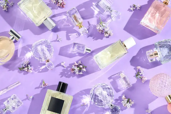 Düz kompozisyon, parfüm şişeleri ve mor arka planda leylak çiçekleri vardı.