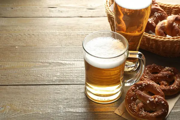 Lezzetli krakerler ve bira kupaları ahşap masada, yakın plan. Metin için boşluk