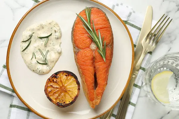 Deniz ürünleri. Sos ile servis edilen lezzetli somon bifteği, biberiye ve limon beyaz mermer masada, düz yatıyordu.